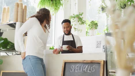 Fröhlicher-Afroamerikanischer-Barista,-Der-Im-Café-Kaffee-Für-Eine-Gemischtrassige-Kundin-Kocht