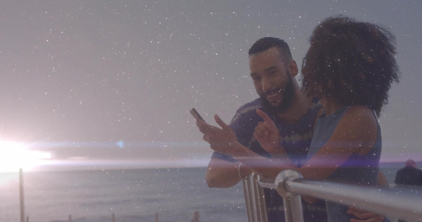 Coppia appoggiata a una ringhiera al tramonto che prende lo smartphone ed esplora la tecnologia per condividere il momento