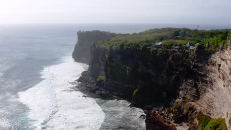 Pequeñas-Olas-Golpeando-La-Línea-De-La-Costa-Del-Acantilado-Con-Una-Exuberante-Vegetación-De-Los-Acantilados-De-Uluwatu-En-Bali-En-Un-Día-Soleado