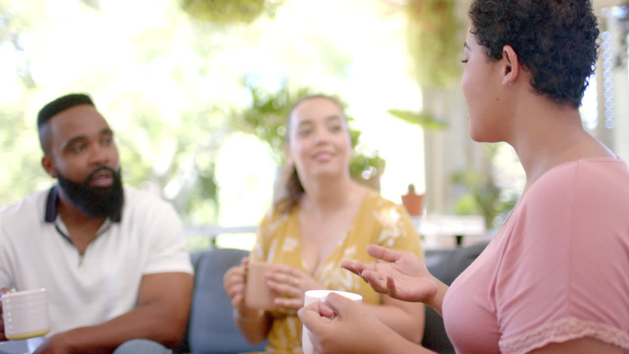 Group of friends sitting on couch, drinking coffee, and talking together