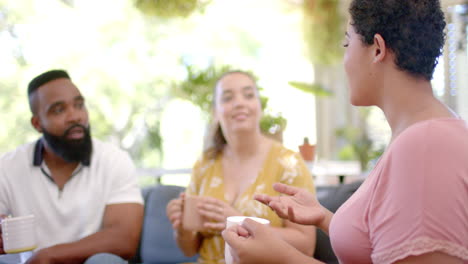 group of friends sitting on couch, drinking coffee, and talking together