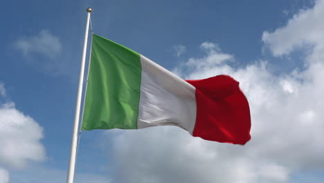 waving almost straight italian green, white and red flag in a strong wind with a royal blue sky and clouds in the background