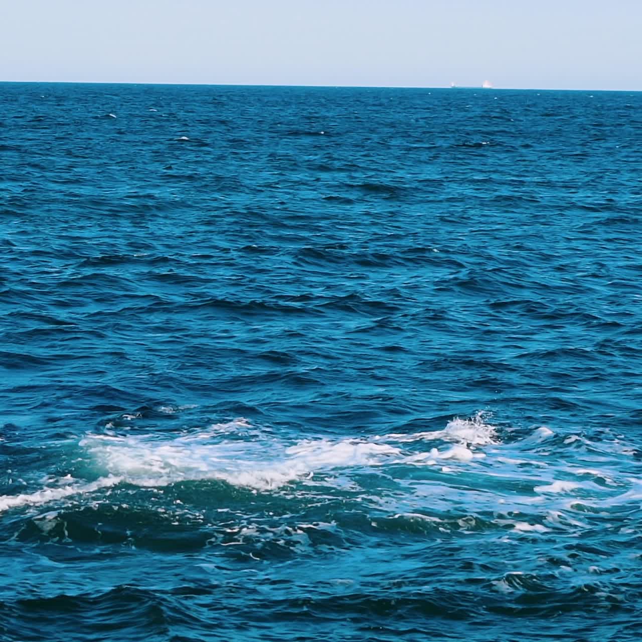 Amazing water background. Waves swaying on the sea water. Beautiful blue water waves with white foam crashing on the dock. Slow motion.
