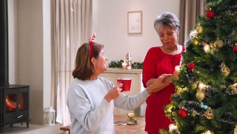 decorating christmas tree, senior women enjoying festive holiday moments together