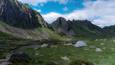 Tienda-De-Campaña-Para-Una-Sola-Persona-En-El-Valle-De-La-Montaña-Cerca-Del-Estanque-Con-Nubes-Pasajeras,-Timelapse