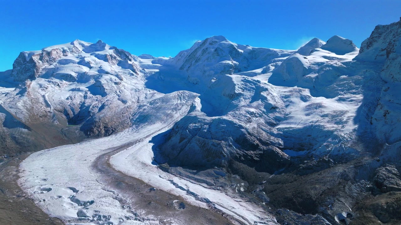 Zermatt Saastal Saas Fee Alpi Svizzere fiume glaciale crepaccio del ghiacciaio Valle del Cervino drone aereo prima nevicata autunno cieli blu mattina presto ferrovia Gornergrat cime montuose panoramica in avanti verso l'alto