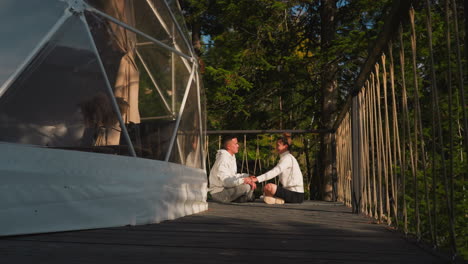 pareja casada medita sentada cara a cara en glamping. hombre y mujer tranquilos hacen yoga juntos visitando el retiro de eco resort. estilo de vida consciente
