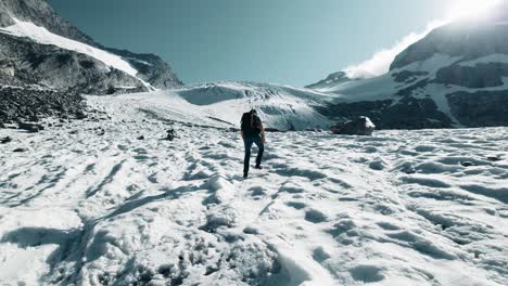 un montañero masculino camina con crampones sobre un glaciar y algunas grietas en el fondo