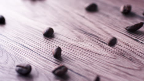 granos de café tostados cayendo sobre una superficie de madera