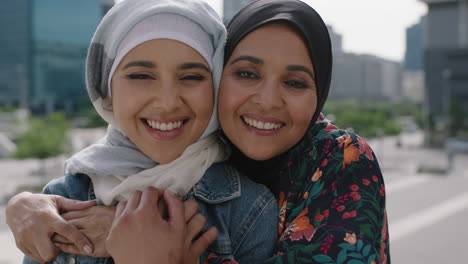 close up portrait of happy mother and daughter smiling cheerful hugging in urban city wearing traditional muslim hajib headscarf enjoying lifestyle