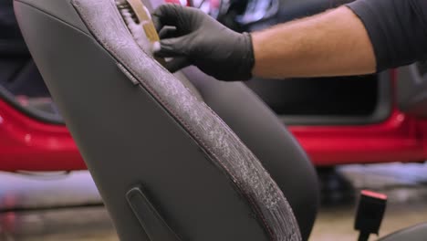 the specialist is engaged in dry cleaning of the removed car seat. mechanic rubbing foam into fabric. stage of complete dry cleaning of the car. detailing center services.