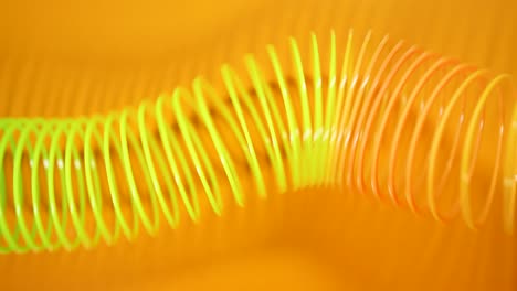 el fondo abstracto retro vintage. el resorte de color arco iris se mueve a través de un fondo naranja en un patrón de onda. juguete slinky. una onda de movimiento de resorte en espiral de arcoirres un fondo brillante y hermoso.