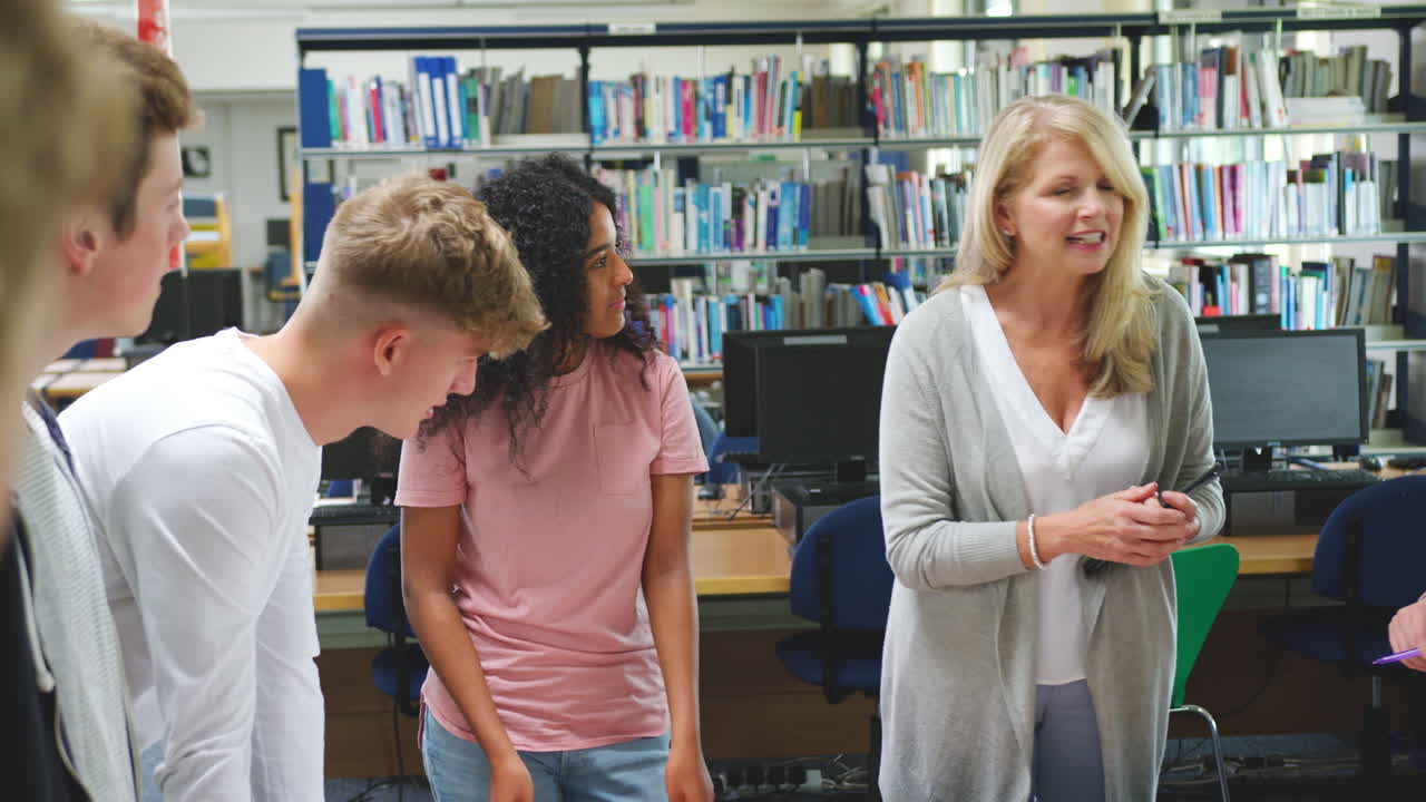 tutora hablando con un grupo de estudiantes universitarios en la biblioteca