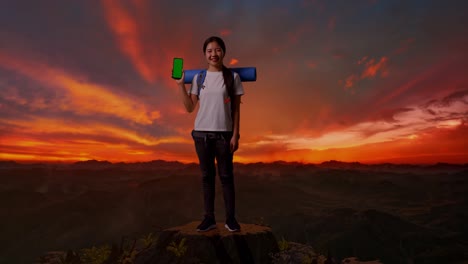 mujer con un teléfono en la cima de una montaña al atardecer
