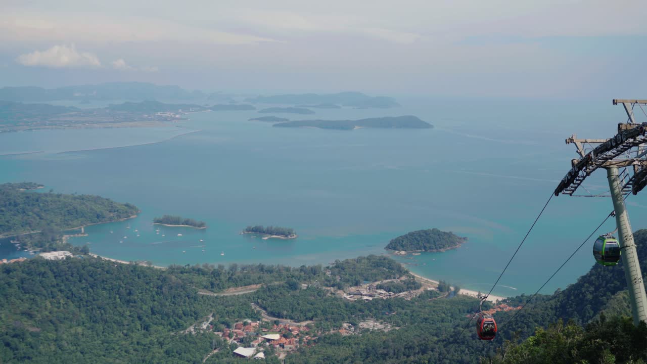 Cable car rises above a vibrant coastline, showcasing langkawi's stunning turquoise waters, verdant islands, and the panoramic beauty of the andaman sea