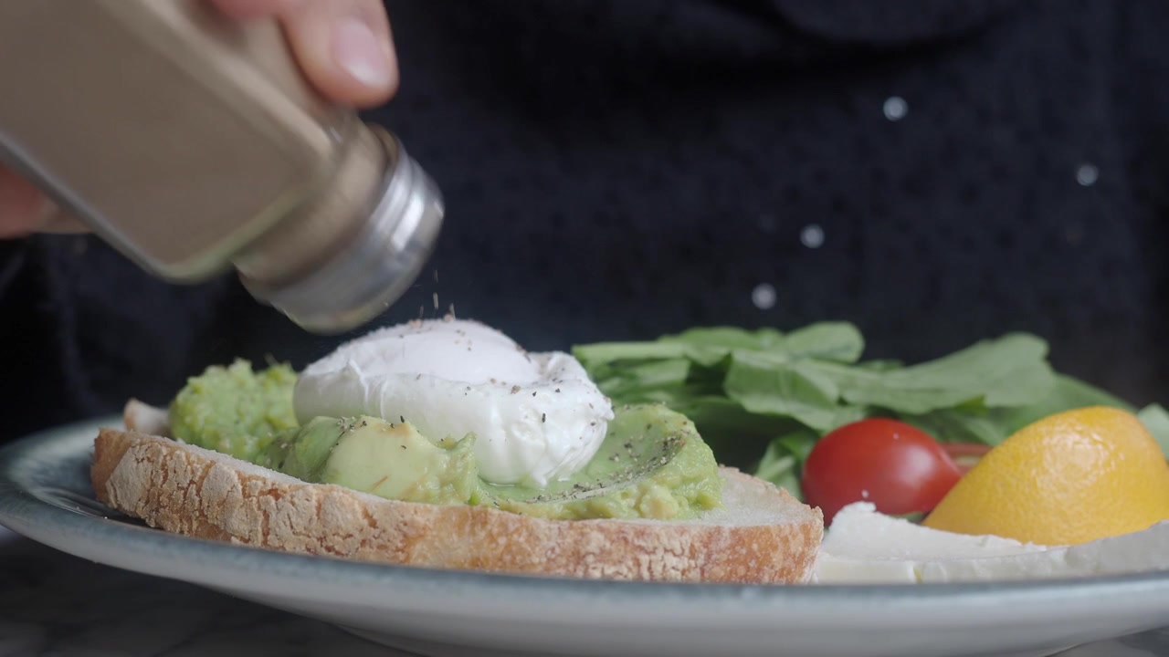 Condire un toast fresco con avocado, uovo in camicia e pepe