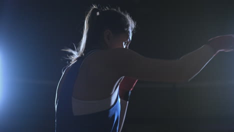 Boxer-woman-in-red-bandages-on-the-hands-of-and-blue-t-shirt-conducts-battle-with-of-practicing-the-speed-and-technique-strikes-hands.-Camera-movement-side-View.-Steadicam-shot