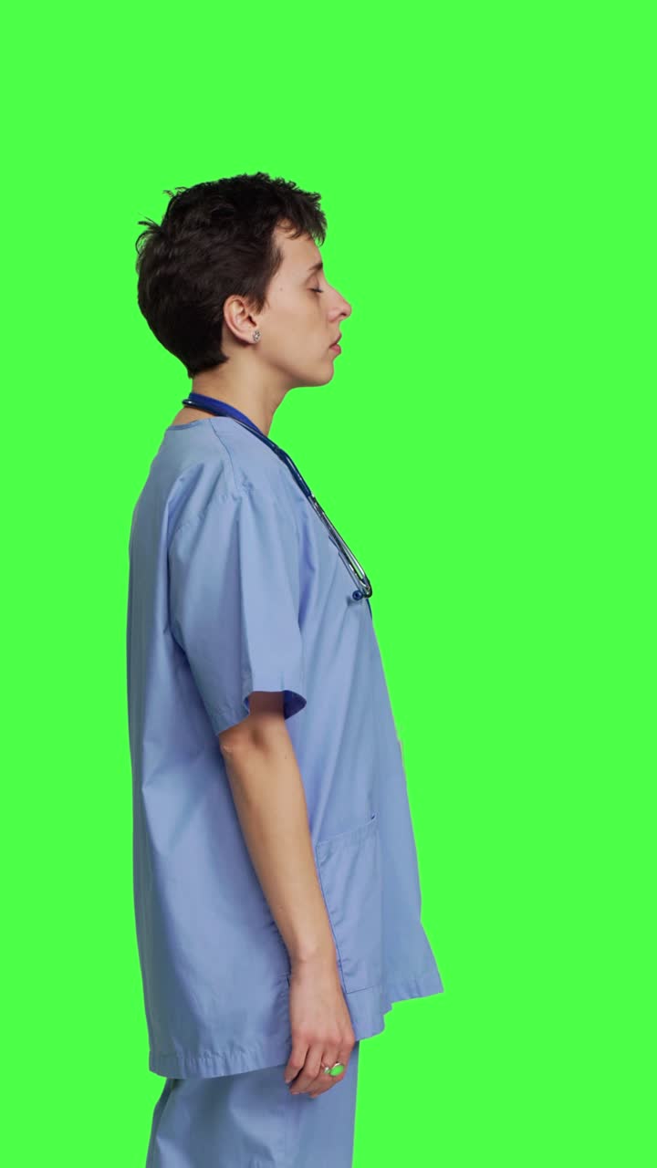 Profile Unwell nurse suffering from a headache against greenscreen backdrop