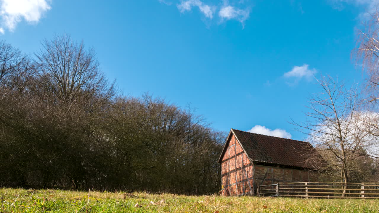 lapso de tiempo de un hermoso y antiguo granero de madera y ladrillo rojo en una granja con un enorme campo de hierba verde cerca de hamburgo en kiekeberg, alemania
