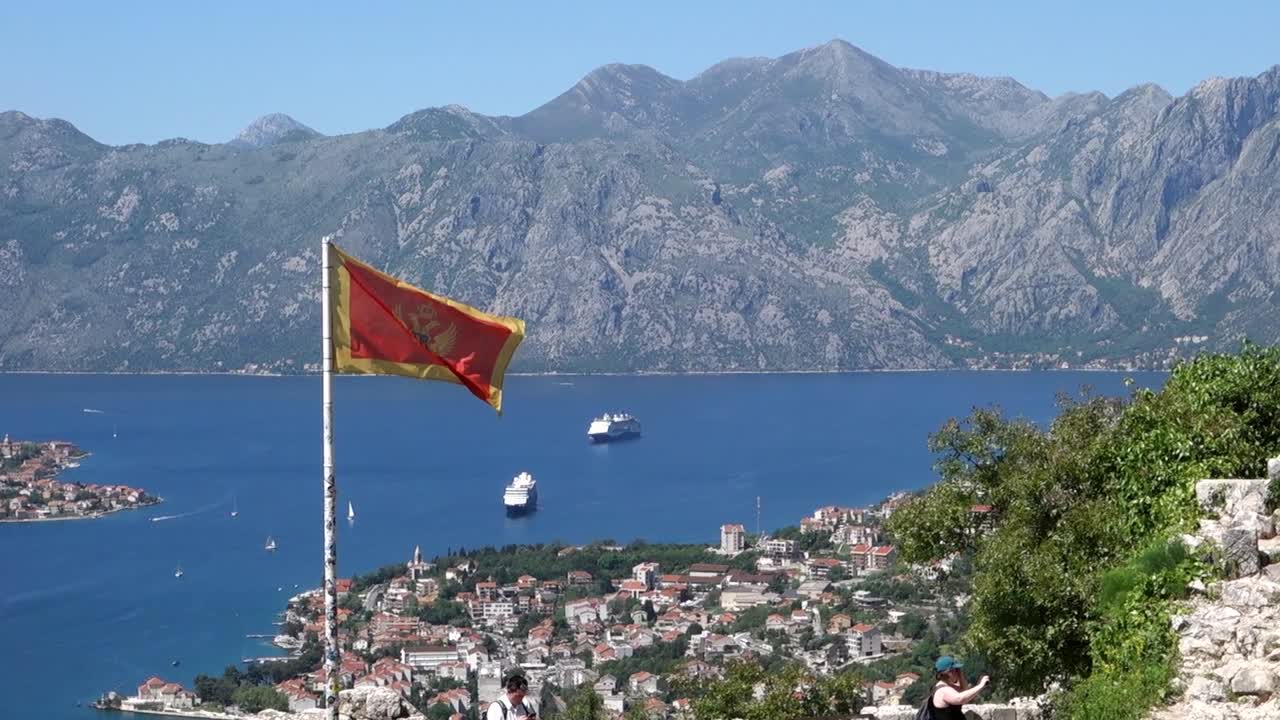 flag of Montenegro flutters over the Bay of Kotor. Kotor Fjord in the background. Montenegro