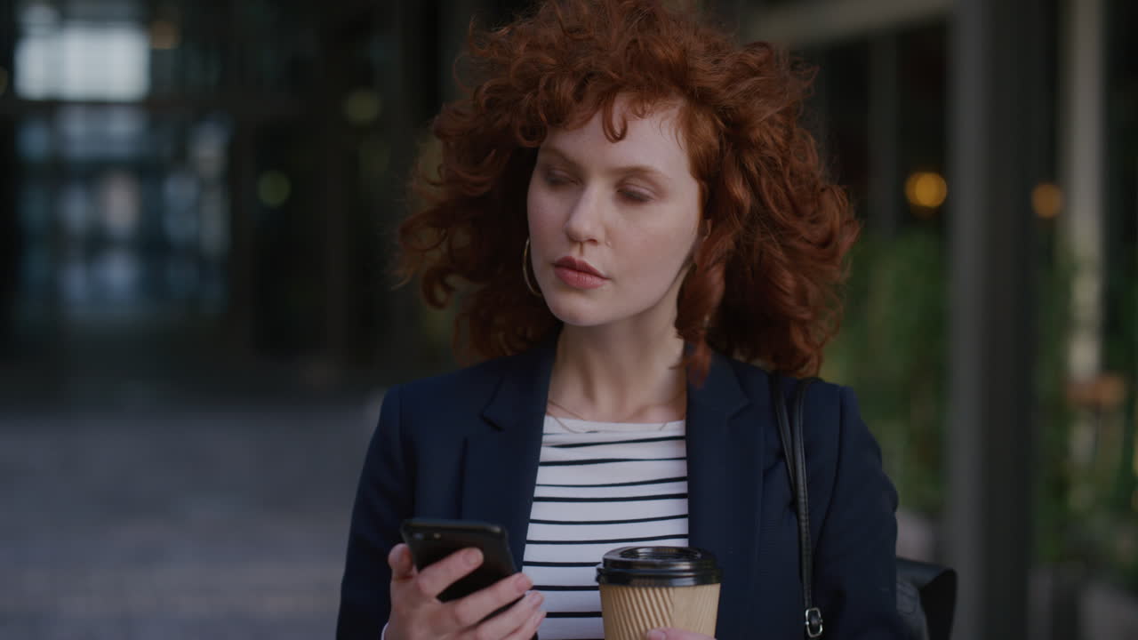 portrait young red head business woman using smartphone in city enjoying relaxing on lunch break texting browsing messages holding coffee slow motion leisure lifestyle