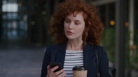 retrato de una joven mujer de negocios de cabeza roja que usa un teléfono inteligente en la ciudad disfrutando de relajarse en la pausa del almuerzo enviando mensajes de texto navegando mensajes sosteniendo café en cámara lenta estilo de vida de ocio