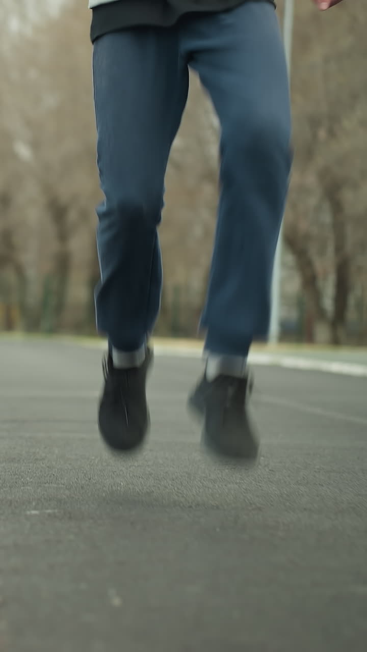Two people jogging side by side on a stadium track, with the person on the left lifting his leg higher than the other person