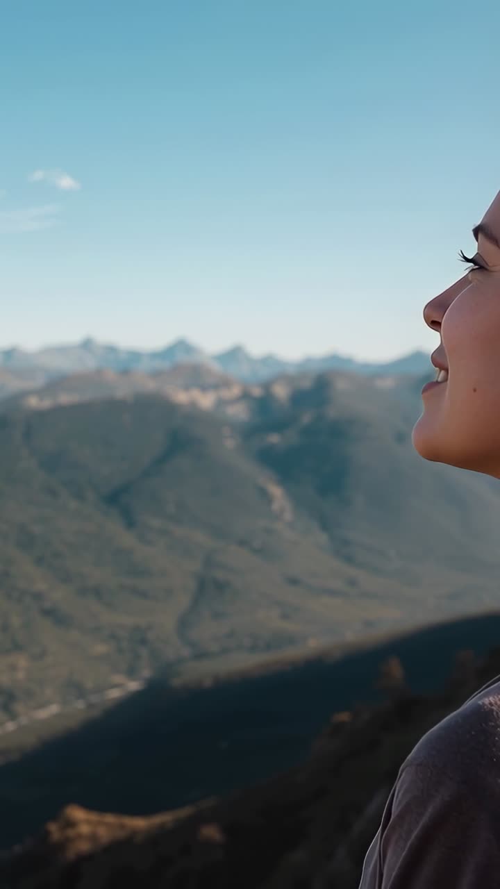 Vídeo vertical: Plano panorâmico mostrando mulher apreciando o vale em um penhasco, vestindo jaqueta escura, com espaço para texto.