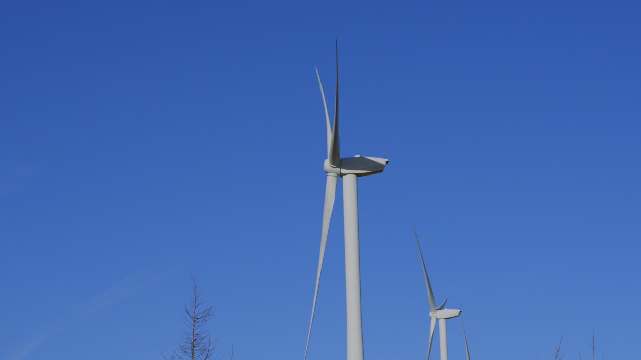 Side View of Large Wind Turbine Spining with Blue Sky Background