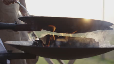 outdoor cooking with a wok over charcoal