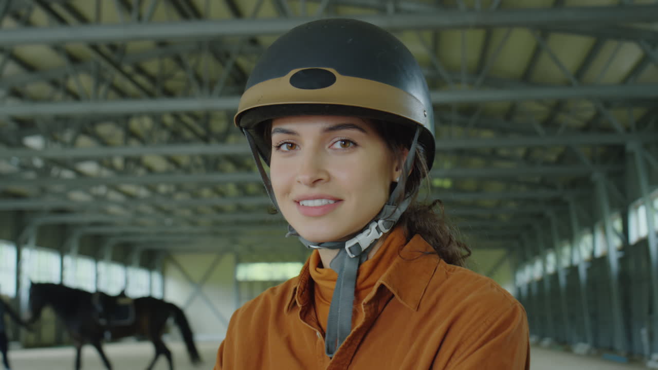 Woman in equestrian helmet in riding arena