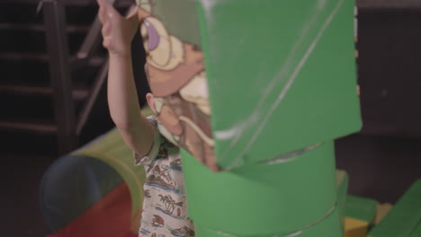 young happy boy building a tall tower with soft play blocks