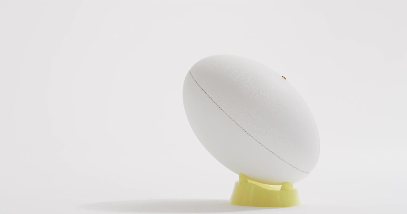 Pallone da rugby bianco su supporto da calcio su sfondo bianco con spazio per il testo, al rallentatore