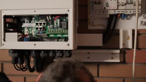 an electrician installing an inverter in a home. the image shows technical skill, modern tools, and attention to safety in electrical work