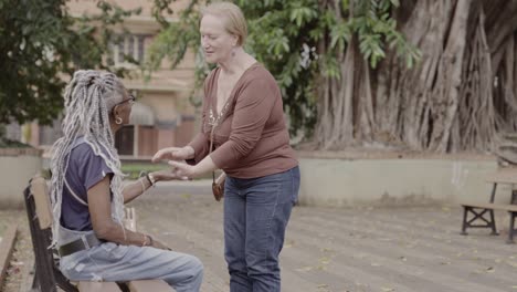 two elderly women share a warm embrace and conversation in a park