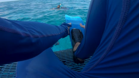 snorkeler putting swimming fins on preparing to snorkel