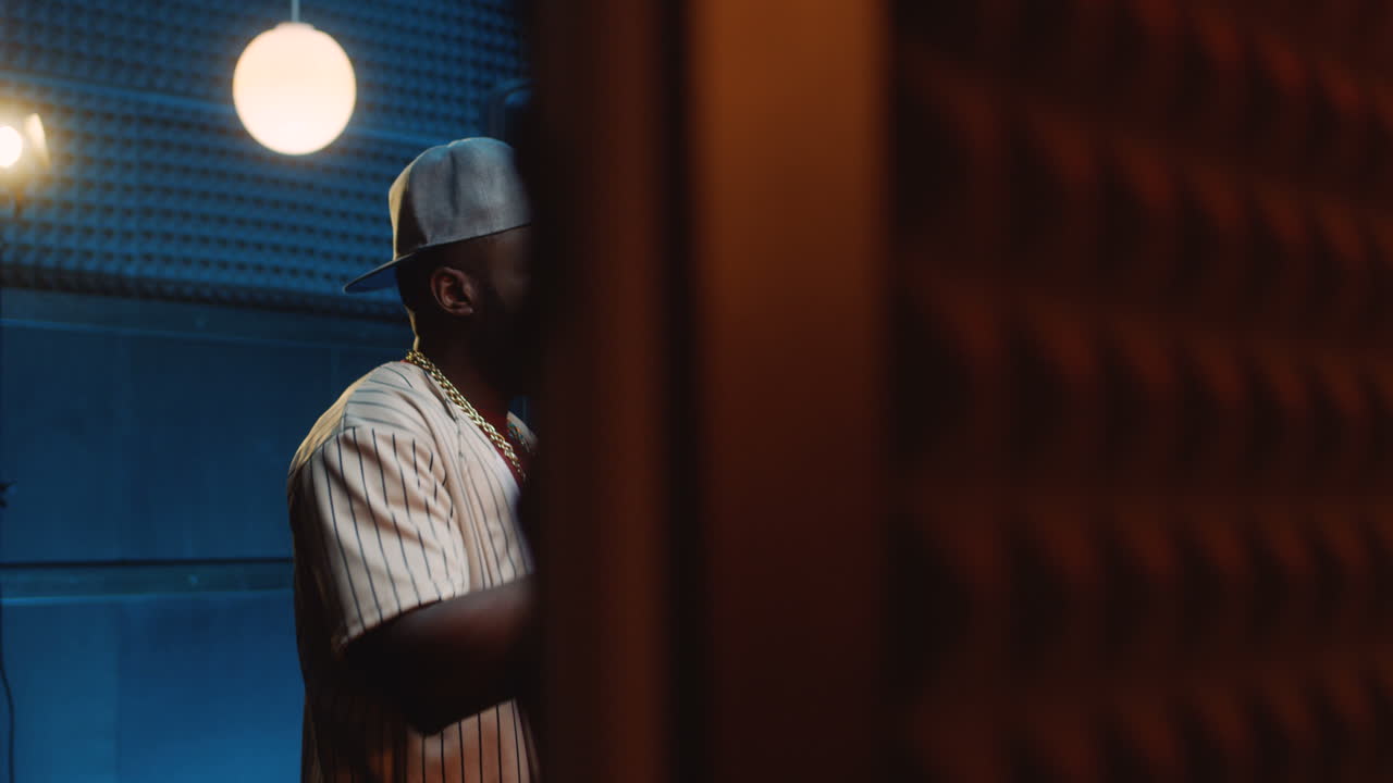 dos raperos jóvenes y guapos grabando una canción en el estudio de sonido oscuro y leyendo rap en el micrófono