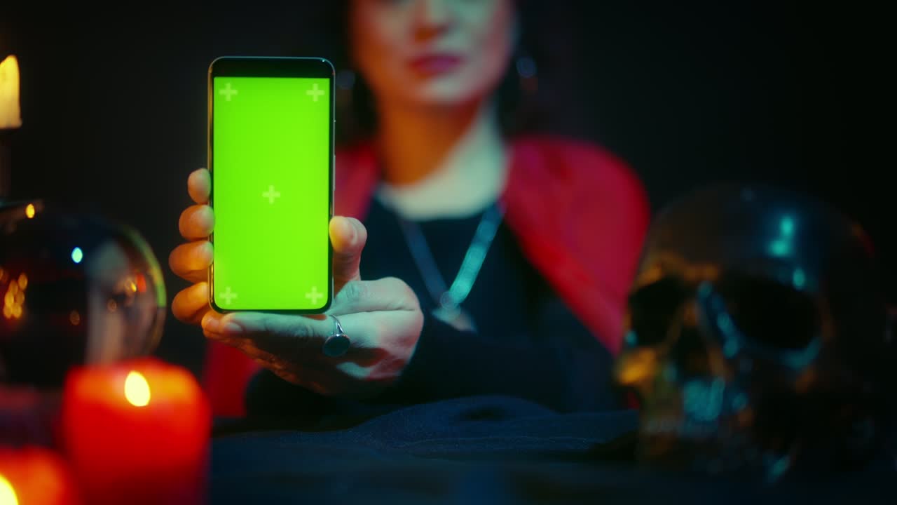 psíquico femenino mostrando teléfono con pantalla verde, sesión de adivinación en línea