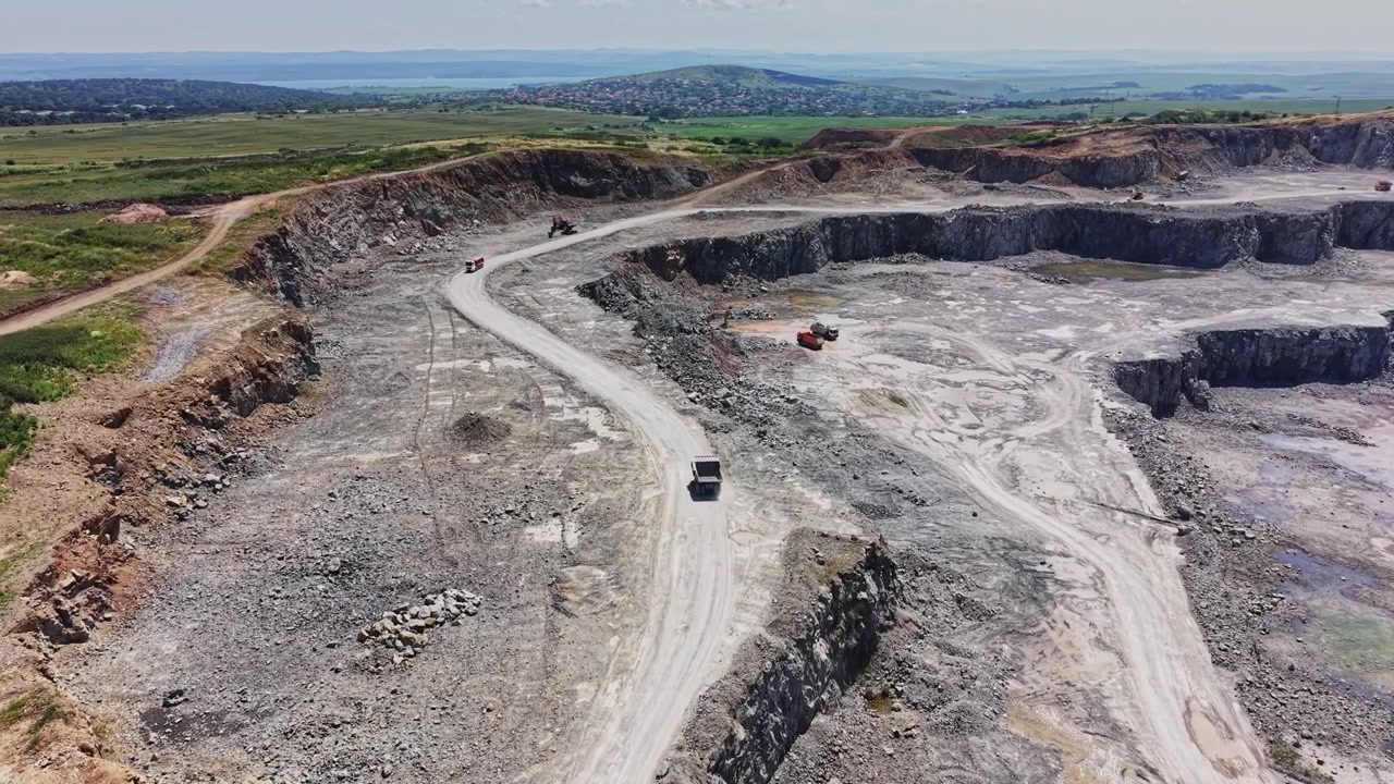 Large quarry with truck on dirt road during daytime in open landscape