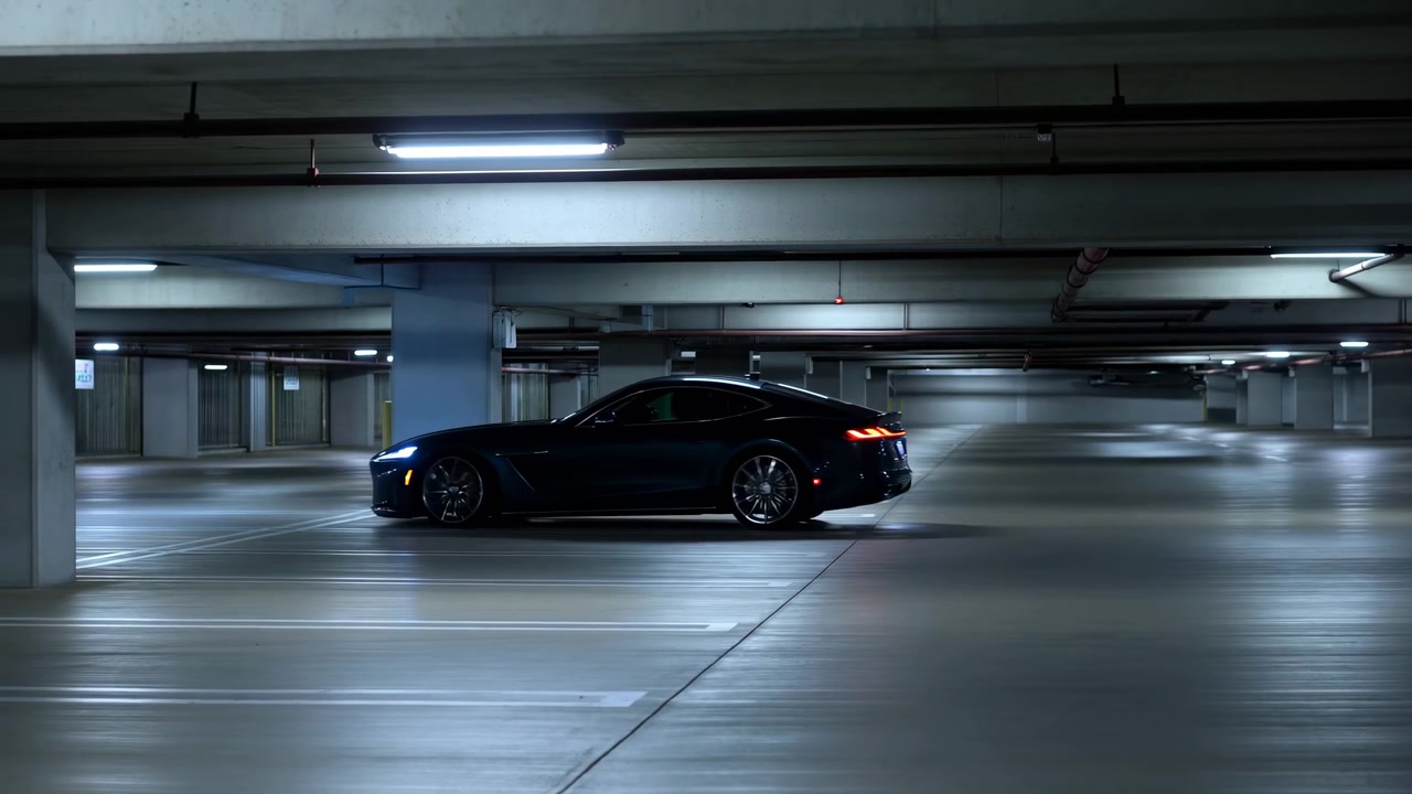 Una berlina nera si muove attraverso un livello di parcheggio in cemento poco illuminato con luminose luci fluorescenti a soffitto che si riflettono sul pavimento lucido e sulle ombre circostanti.