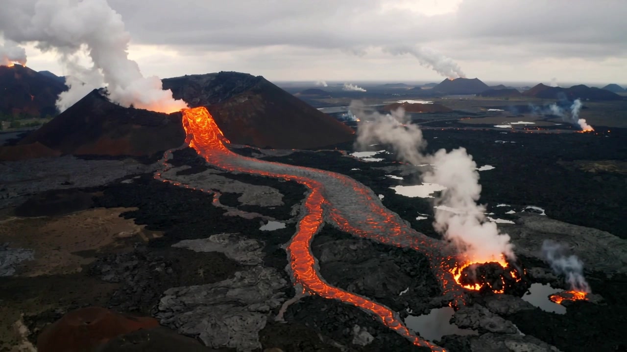 Cono vulcanico in eruzione che invia lava fusa che scorre giù su una remota pianura lavica, emettendo vapore.