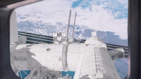 view from an iss window showing the space station and planet earth below