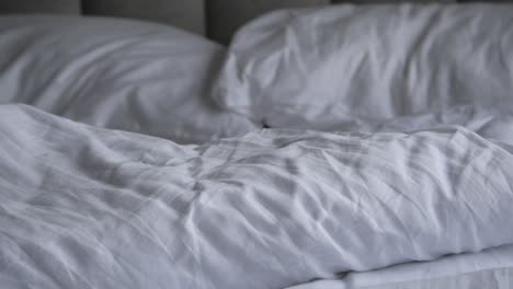 unmade bed with white sheets and pillows