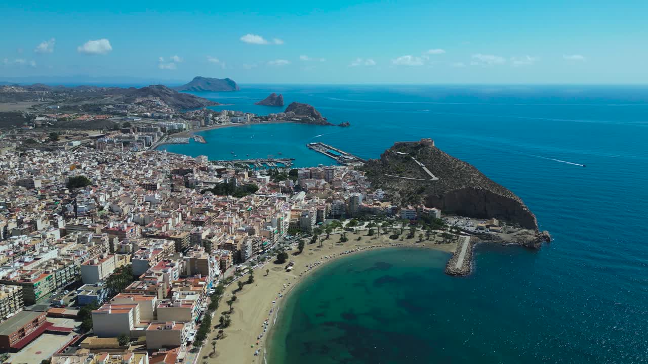 Aerial footage of the coastline and Castillo de San Juan de las Águilas overlooking the beaches and harbour of Águilas in the Murcia region of Spain