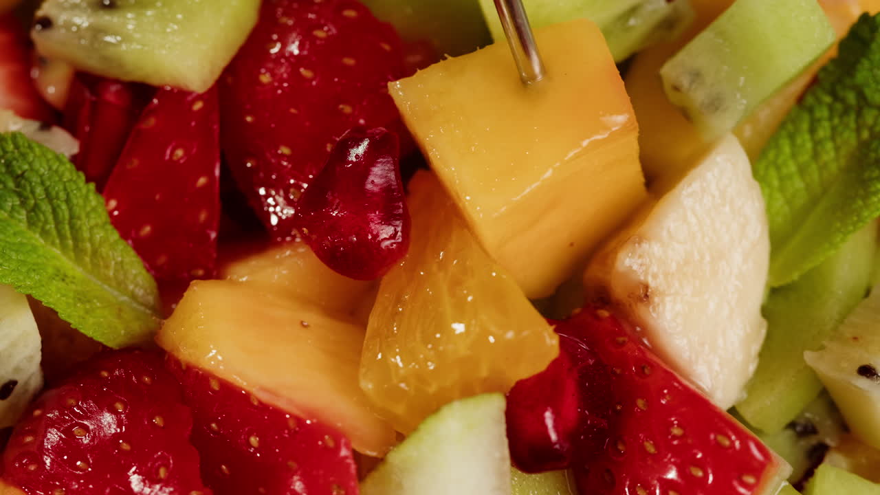 Picking a Piece of Mango from a Vibrant Fruit Salad