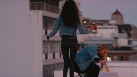 beautiful young woman friends walking on rooftop edge drinking alcohol enjoying girls night out in city