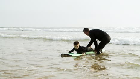 father teaching son surfing on waves