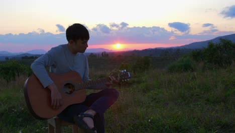 musician performing with acoustic guitar at sunset and horizon in background, vietnam