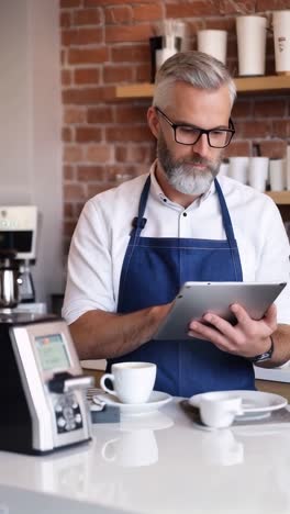 cafeteria owner in blue apron using a tablet. small business.
