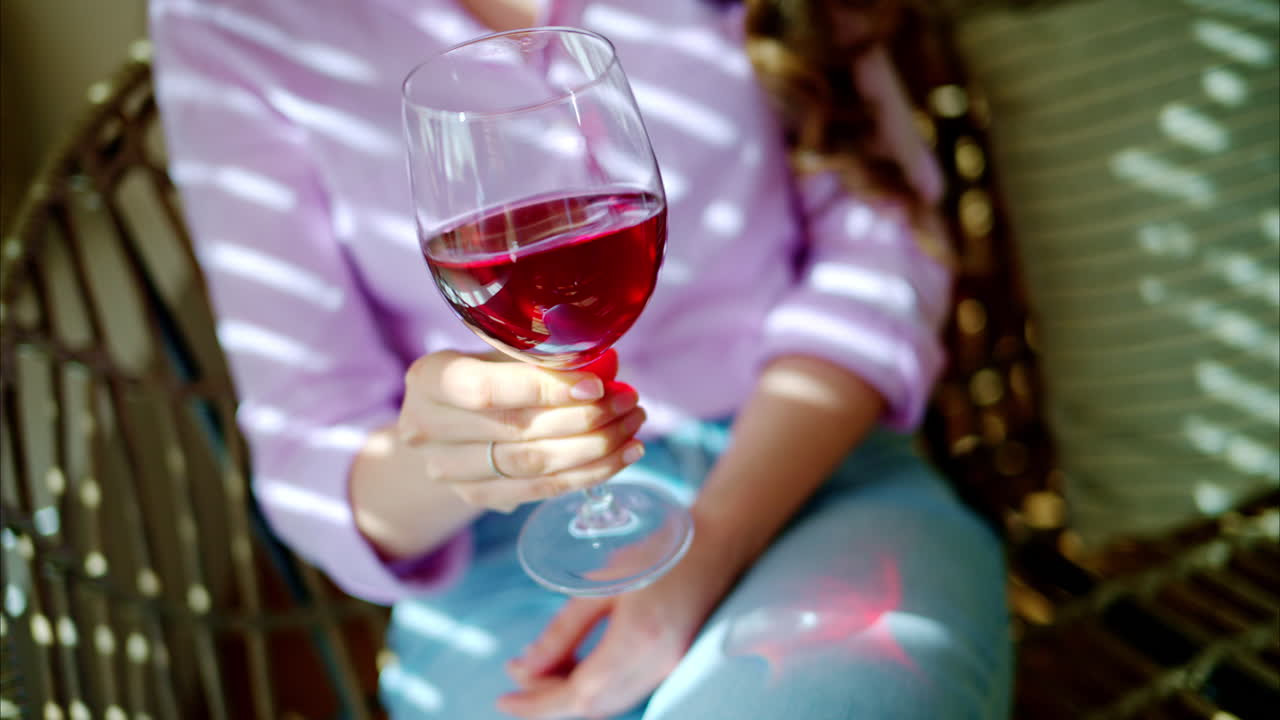Woman swirling a glass of red wine in daylight